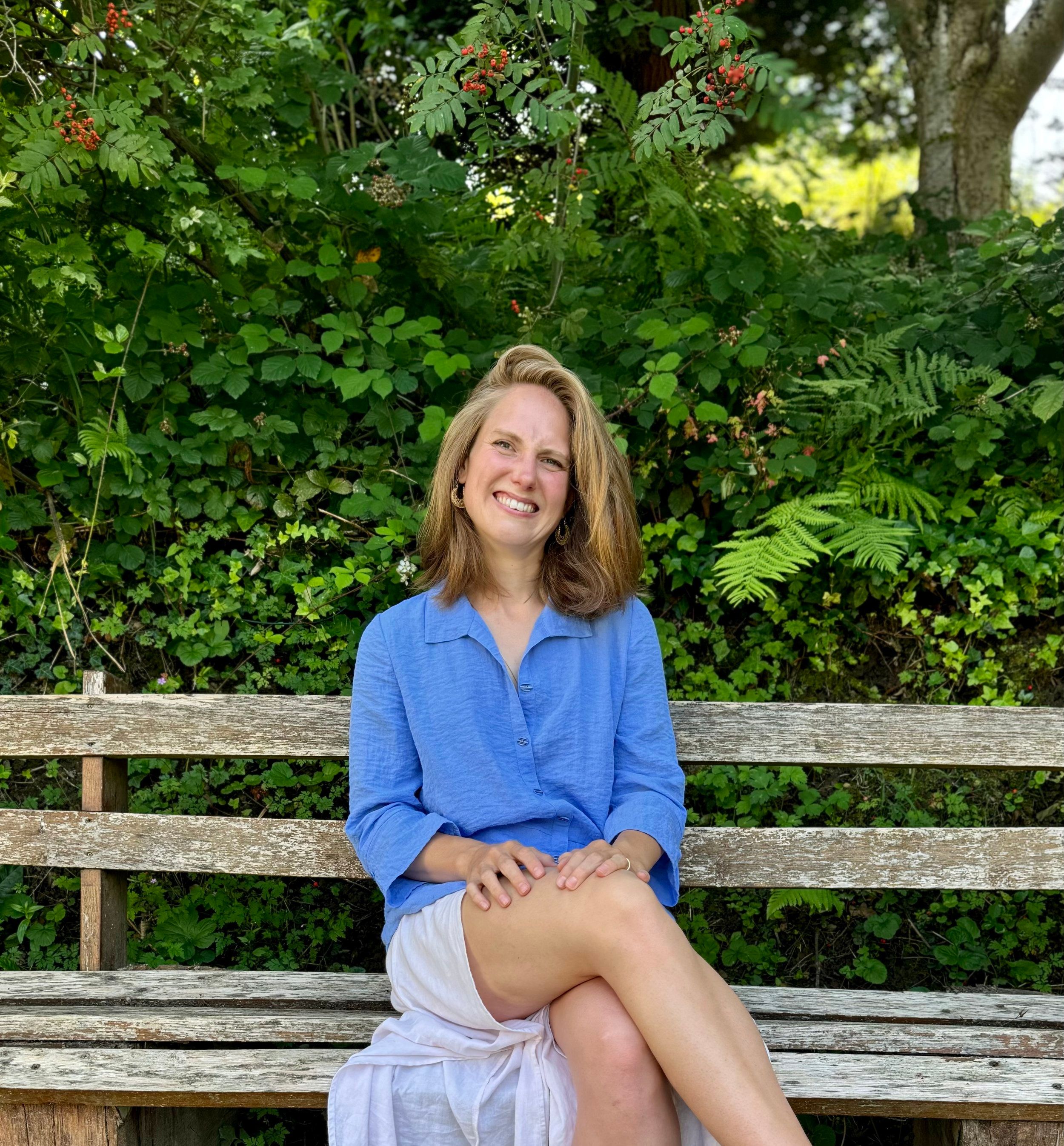 Katherine Kaufmann smiling on a wooden garden bench